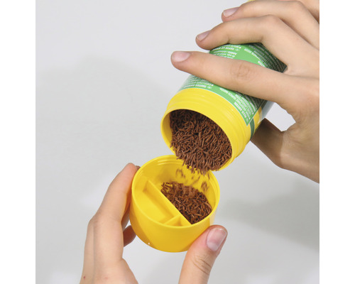 Fischfutter wird in einen gelben Dosierer gefüllt