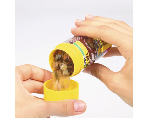 JBL NovoBel Flockenfutter wird in einen gelben Deckel gegossen