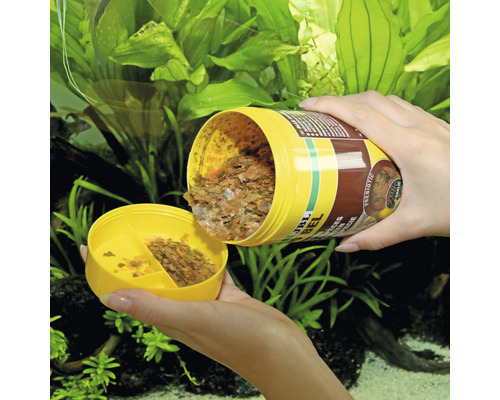 Nourriture en flocons JBL NovoBel pour poissons d''ornement versée dans une boîte jaune.