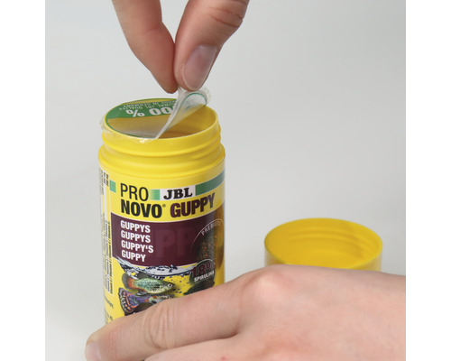 Das Foto zeigt, wie ein Behälter JBL Pro Novo Guppy Fischfutter geöffnet wird.