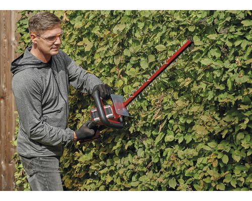 Eine Person schneidet eine Hecke mit einer Heckenschere.