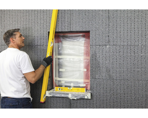 Mann prüft Fenster mit Wasserwaage auf Dämmplatten