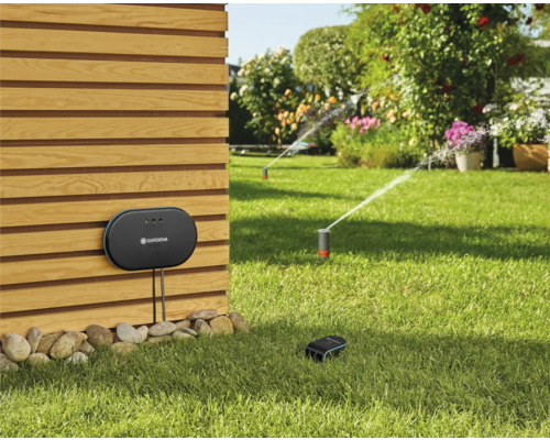 Gardena Smart System avec centrale de commande, capteur et arroseur de gazon dans le jardin.