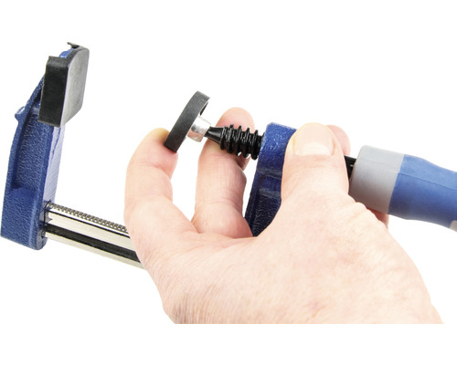 Eine Schraubzwinge wird von einer Hand bedient.