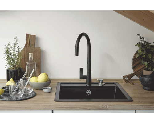 Scène de cuisine avec évier, robinet et éléments décoratifs sur un plan de travail.