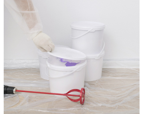 Plusieurs seaux de peinture blancs avec mélangeur de peinture et film de protection.