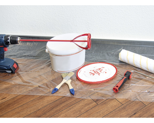 Seau de peinture, agitateur, perceuse, rouleau à peinture et pinceaux sur une feuille