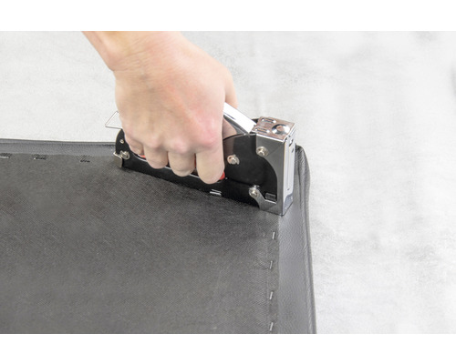 Handhabung eines Handtackers auf einem schwarzen Stoff