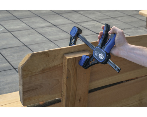 Main tenant un serre-joint à une main sur du bois