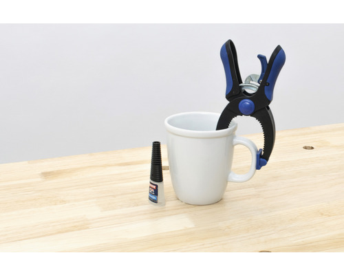 Serre à ressort, colle et tasse sur table en bois
