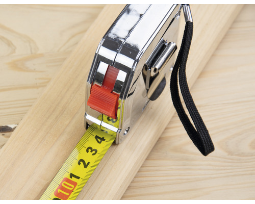 Un mètre ruban repose sur une planche de bois.