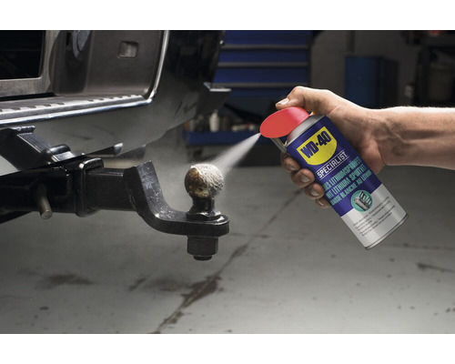 Eine Person sprüht Lithiumspray aus einer WD-40 Dose auf eine Anhängerkupplung.