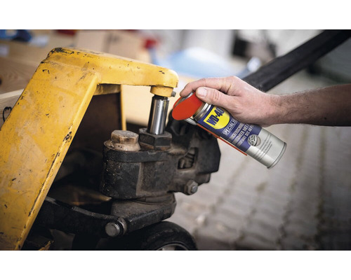 Eine Person sprüht Trockenschmiermittel von WD-40 auf einen Hubwagen