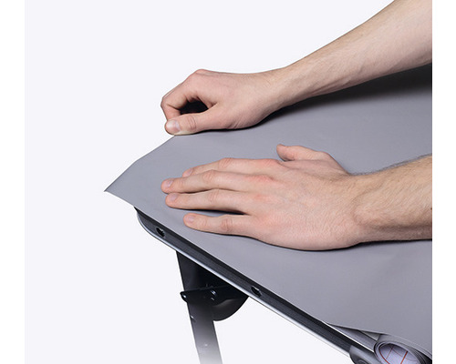 Person befestigt eine Tischfolie auf einem Tisch