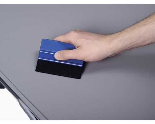 Hand verwendet Rakel zum Glätten einer Oberfläche