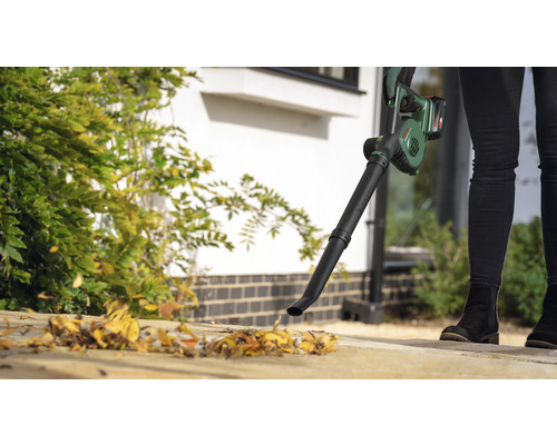 Person verwendet einen Akku-Laubbläser zur Gartenarbeit.