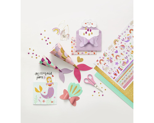 Divers matériel de bricolage pour une fête sur le thème des sirènes sont posés sur une table, notamment des chapeaux de fête, des invitations, des autocollants, des ciseaux et des confettis.