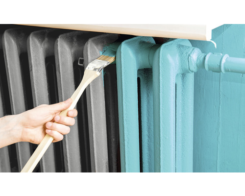 Eine Person streicht einen Heizkörper mit einem Pinsel.