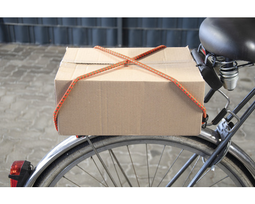 Un carton est fixé à un vélo avec un tendeur.