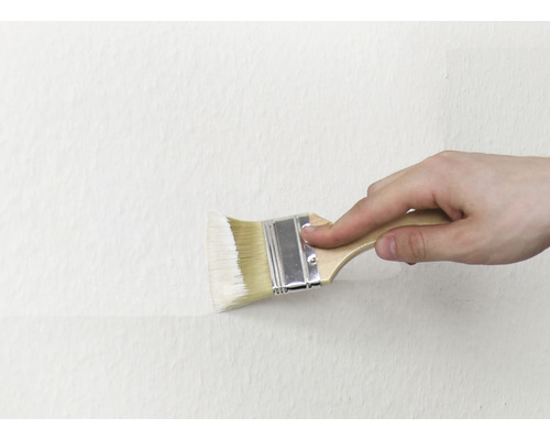 Une personne peint un mur avec un pinceau.