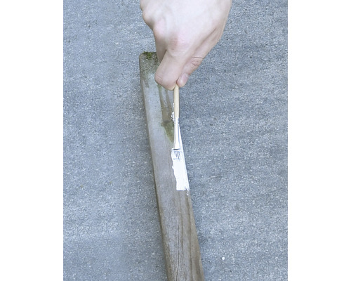 Peinture d''un poteau en bois avec un pinceau