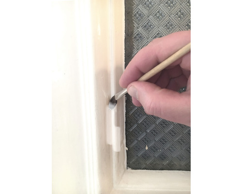 Un pinceau est utilisé pour appliquer de la peinture sur un cadre de fenêtre.