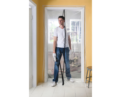 Un homme se tient dans une embrasure de porte avec une porte anti-poussière