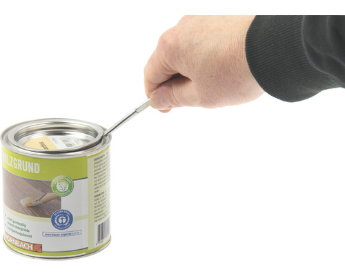 Une personne ouvre une boîte d''apprêt pour bois avec un outil