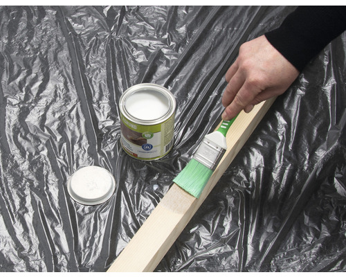 Peinture d''une pièce de bois avec un pinceau et un pot d''apprêt pour bois.