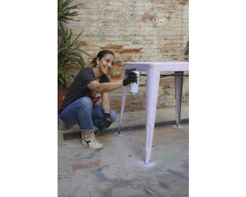 Femme vaporisant de la peinture sur une table à l''extérieur.