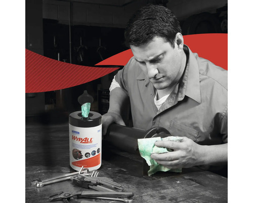 Un homme nettoie une surface avec un chiffon, à côté de lui se trouve une boîte distributrice de chiffons de la marque Wypall.