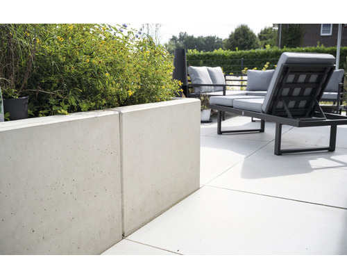 Espace extérieur avec jardinière en béton et mobilier de jardin.