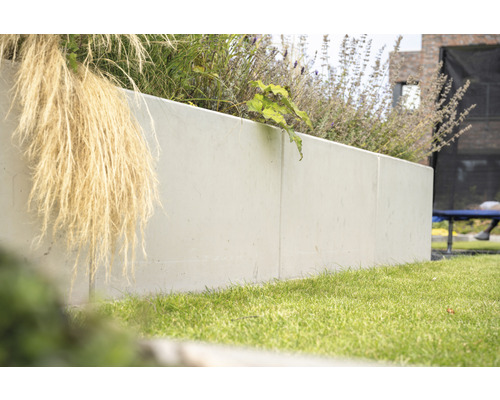 Jardinière haute en béton avec des plantes dans le jardin