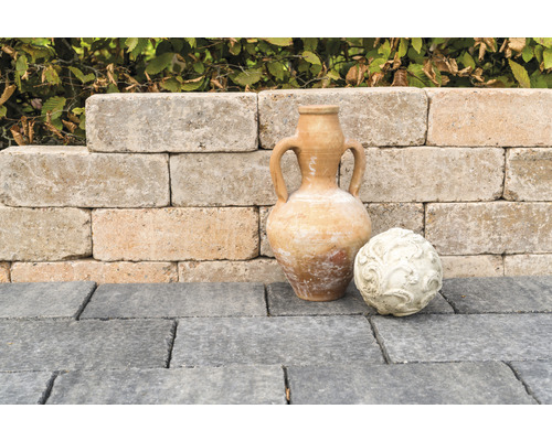 Mur de jardin avec amphore décorative et boule ornementale sur pavés