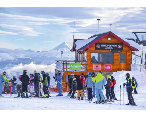Des skieurs se tiennent devant une cabane en bois avec l''inscription Service de Pistas dans un paysage de montagne enneigé