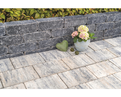 Des pierres de mur empilées forment un petit mur, complété par des dalles de trottoir et des éléments décoratifs