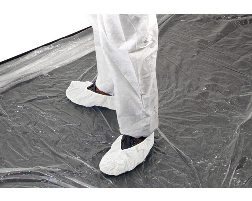 Personne portant une combinaison de protection et des couvre-chaussures sur une feuille transparente