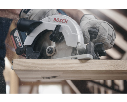 Akkukreissäge beim Schneiden von Holz mit Spänen und Bediener mit Schutzhandschuhen.