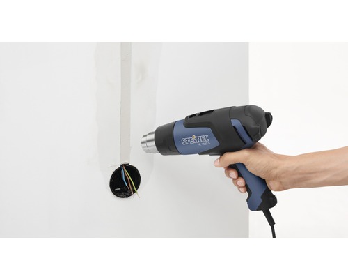 Une personne utilise un pistolet thermique Steinel, modèle HL 1620 S, sur un mur avec une boîte électrique