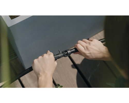 Une personne connecte un tuyau d''irrigation à un raccord.