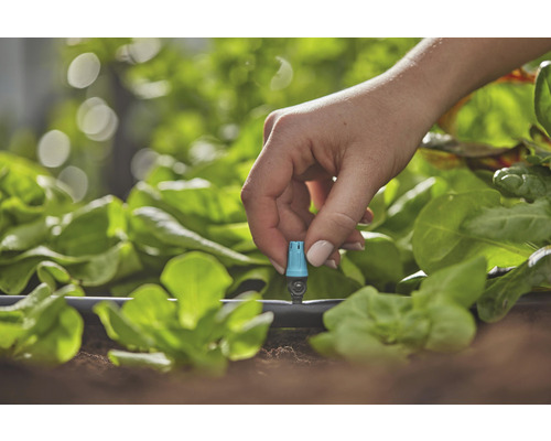 Nahaufnahme einer Hand, die ein Bewässerungssystem im Garten einstellt
