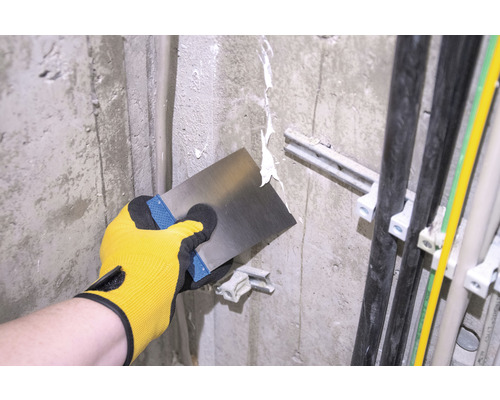 Handwerker verspachtelt eine Wand mit einem Spachtel.