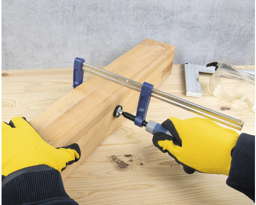 Holzbearbeitungsszene mit Schraubzwinge und Handschuhen