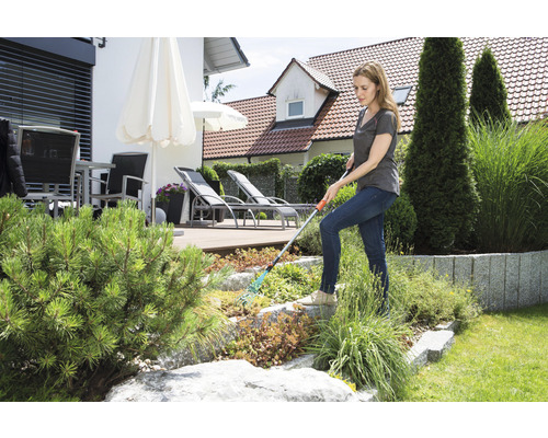 Une femme travaille avec un râteau dans le jardin.