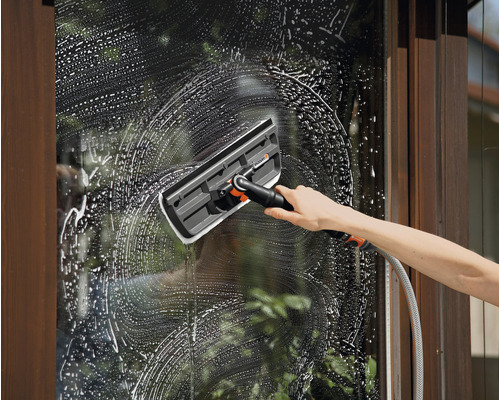 Une personne nettoie une fenêtre avec un lave-vitre, en utilisant de l''eau savonneuse.