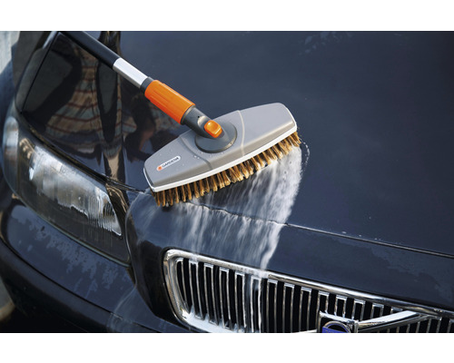 Brosse de lavage Gardena avec manche télescopique nettoyant une voiture.