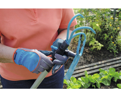 Personne avec des gants de jardin tenant une houe