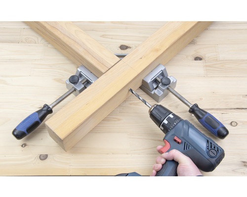 Holzbearbeitungsszene mit Bohrmaschine und Eckspanner zur Holzverbindung.