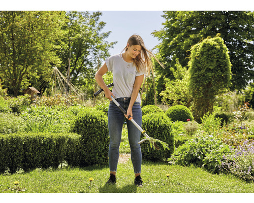 Femme utilisant un désherbeur dans le jardin.