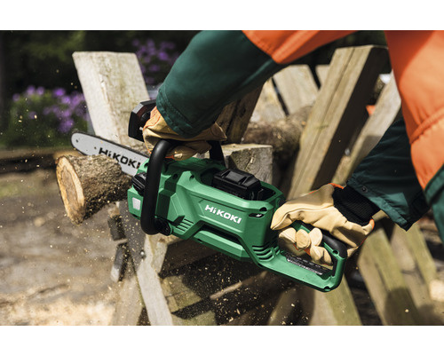 Eine Person sägt mit einer grünen Akku-Kettensäge von HiKOKI Holz.
